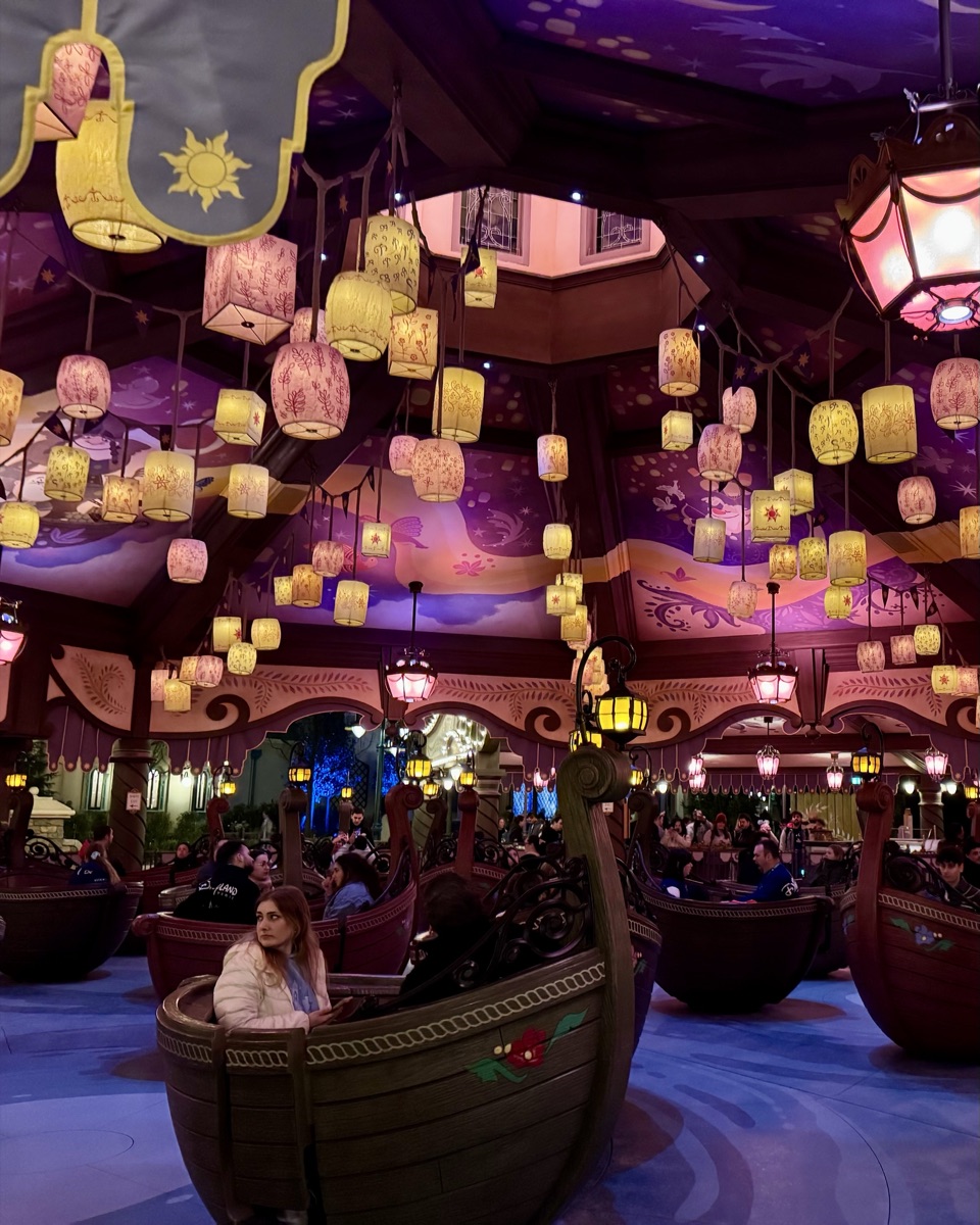Inside Raiponce Tangled Spin at Disney Adventure World, showing spinning gondolas under a ceiling of golden lanterns